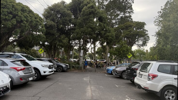 Page Street at Clifton Hill Primary School during school drop-off: cars parked on both sides, families and bikes at the modal filter barrier in the background